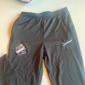 Svarta AIK- träningsbyxor från Nike - Säljer ett par svarta träningsbyxor från Nike med AIK logga. Något slitet på ena knät.