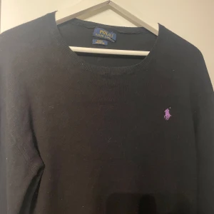Svart tröja från Polo Ralph Lauren - Säljer en stilren svart tröja från Polo Ralph Lauren i slim fit. Den är gjord av mjuk pima bomull och har en lila broderad logga på bröstet. Perfekt för både vardag och fest! Priset är diskuterbart 🖤