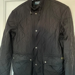 Svart quiltad jacka från Polo Ralph Lauren - Säljer en snygg svart quiltad jacka från Polo Ralph Lauren i storlek S. Jackan har långa ärmar och praktiska knappar framtill. Perfekt för höst och vår, med en stilren design som passar till det mesta. Håll dig varm och trendig! 🖤