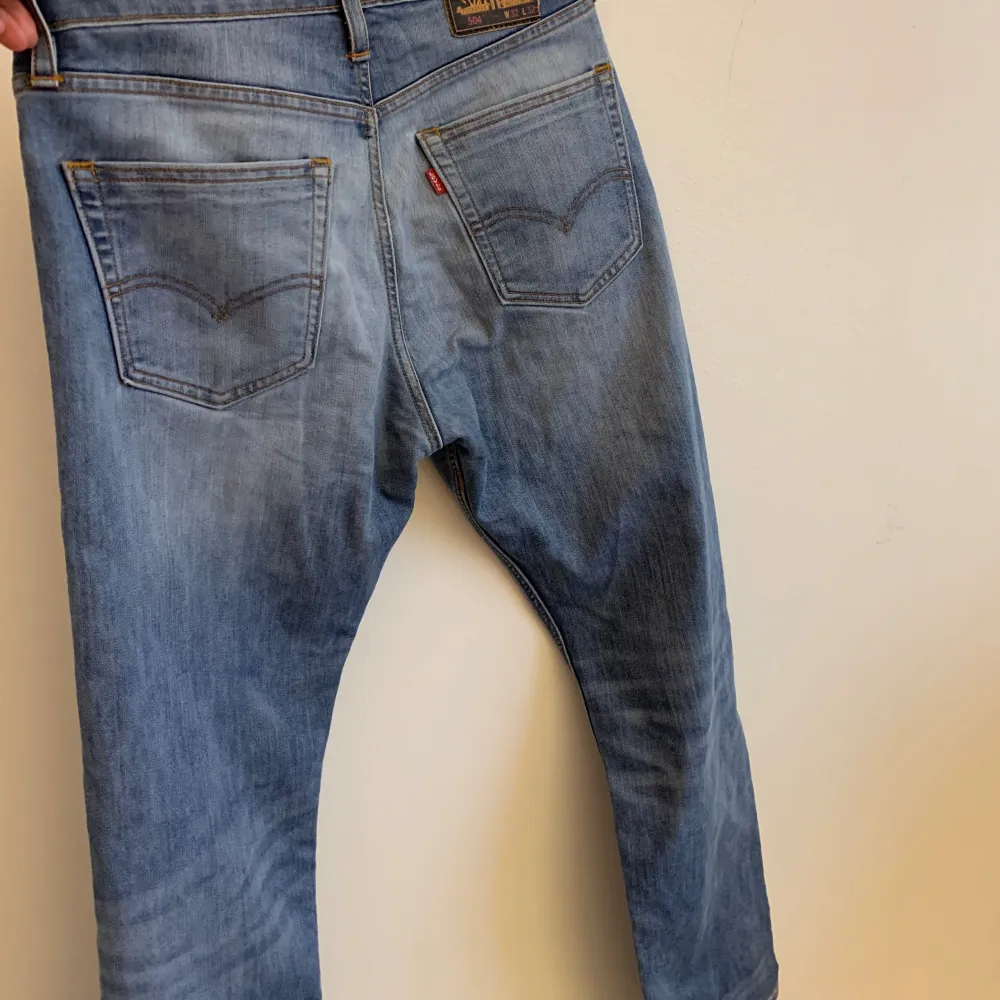 Säljer ett par Levi's 504 jeans i ljusblå tvätt. De har en klassisk femficksdesign och är i bra skick. Perfekta för vardagsbruk med en straight passform som ger en avslappnad look. Passar både till sneakers och boots.. Jeans & Byxor.