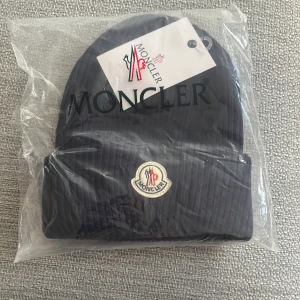 Moncler mössa(mörkblå) - Säljer en riktigt fin mössa av moncler helt oanvänd fortfarande i förpackning också.
