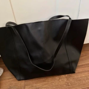 Svart axelväska i skinn - Säljer en stilren svart axelväska i skinn. Perfekt för vardagsbruk med gott om plats för böcker och andra nödvändigheter. Väskan har en enkel design med en knappstängning för säker förvaring. Passar till alla tillfällen och är lätt att matcha med olika outfits. Perfekt inför skolan. Köptes för 600, säljer för 350. Är i bra skick 💕