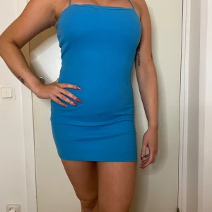 Blå ribbad klänning - Snygg blå ribbad klänning med smala axelband. Perfekt för sommarens fester eller en utekväll. Den är tight och kort, vilket ger en smickrande passform. Klänningen är i ett mjukt och stretchigt material som gör den bekväm att bära hela dagen.