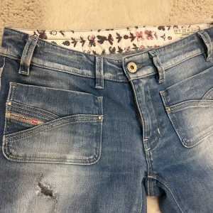 Lågmidjade jeans från Diesel - Säljer dessa såå snygga jeansen från diesel som tyvärr inte passade mig. (Andra bilden är lånad från den jag köpte av) De har en cool slitning på ena benet och en liten reva vid fickan. Jeansen är lågmidjade och har en straight passform. Midjemåttet rakt över är 36cm och innerbenslängden ca 77cm💕