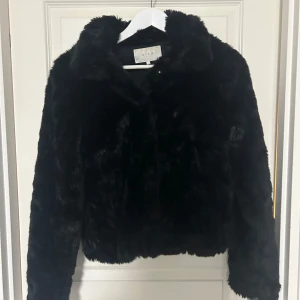 Svart pälsjacka  - Säljer en supermjuk och fluffig svart pälsjacka från Vila. Den är perfekt för att hålla sig varm och stilren under kyliga dagar. Jackan har en klassisk krage och långa ärmar, vilket gör den både elegant och bekväm. Väldigt varm och mysig för vinterhalvåret