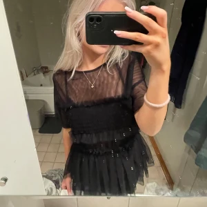 Svart festtopp med volangdetaljer - Säljer en superfin svart topp med volangdetaljer. Passar perfekt för en utekväll eller fest!