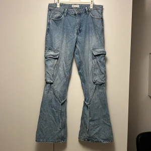 Utsvängda cargojeans - Säljer ett par snygga blåjeans med cargo-känsla från Zara i storlek 40, sitter som 38 skulle jag dock säga. Byxorna har vida ben och två stora fickor samt ett spänne som hänger runt vaden. Jag är 175cm lång. Bra skick, inga defektheter🩷(De är nytvättade på bilderna så därför de är lite skrynkliga!😅)