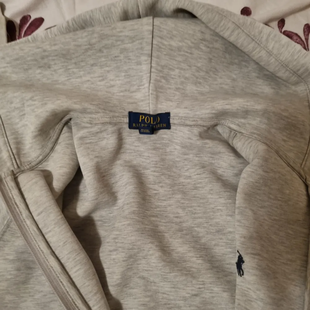 Säljer en snygg och bekväm grå hoodie från Polo Ralph Lauren. Den har en dragkedja framtill och en klassisk logga på bröstet. Perfekt för både vardag och chill. Den är i bra skick och passar till alla tillfällen!. Hoodies.