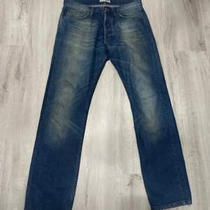 Säljer ett par snygga blå jeans från Acne Jeans i storlek 31/32. De har en klassisk straight fit och är tillverkade i 100% bomull, vilket gör dem både bekväma och hållbara. Perfekta för vardagsbruk och kan enkelt matchas med olika outfits. Passa på att fynda dessa stilrena jeans!