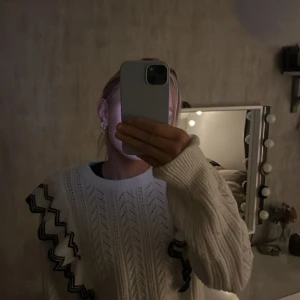 Vit stickad tröja med volangdetaljer - Säljer en superfin vit stickad tröja med unika volangdetaljer längs ärmarna. Perfekt för höst och vinter, den är både varm och stilren. Tröjan har ett snyggt mönster och långa ärmar, vilket gör den idealisk för kyligare dagar. Passar perfekt till både jeans och kjol!