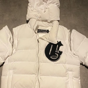 Vit Corvidae tredels puffer  - Säljer en snygg vit pufferjacka från Corvidae. Jackan är praktiskt och kan delas till en väst. Den kan även användas med eller utan luvan. Perfekt för kallt väder eller höst/vår med sin varma och puffiga design. Storlek S, köpt på Plick förra vinter för 2500. 