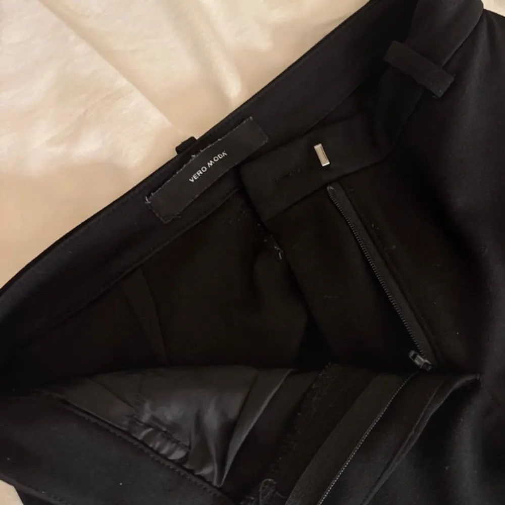 Snygga svarta kostymbyxor från Vero Moda i ett klassiskt snitt. De har en dragkedja fram och är perfekta för både jobb och fest. Byxorna är i ett mjukt och bekvämt material som ger en elegant look. Passar perfekt till en skjorta eller blus för en stilren outfit.. Farkut & Housut.