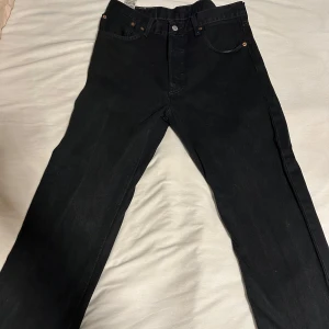 Svarta Levis 501 jeans W32 L32 - Säljer ett par klassiska svarta Levis 501 jeans i mycket bra skick. De har en straight passform och är tillverkade i slitstarkt denim. Perfekta för både vardag och fest! Storlek W32 L32! Bara höra av sig 