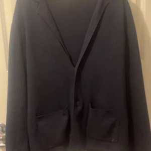 Mörkblå cardigan från WE fashion - Säljer en stilren mörkblåa cardigan från WE fashion i storlek M (sitter nästan bättre som L). Köptes för någon månad sen från Zalando för cirka 700kr. Säljer denna då den inte satt så bra på mig. Har används ett fåtal gånger. Är som en helt ny!