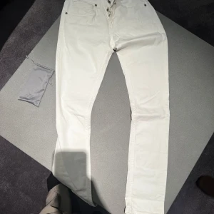 Vita jeans från Dondup - Säljer ett par snygga vita jeans från Dondup i storlek 28. De har en slim fit och är perfekta för både vardag och fest. Byxorna har klassiska fem fickor och knappar i midjan. De är i mycket bra skick och redo för en ny ägare!
