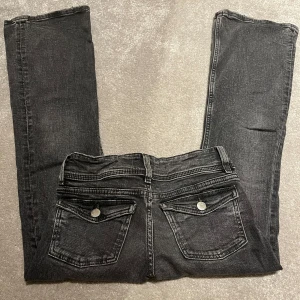 Mörkgrå Gina Tricot jeans med bootcut - Min lillasyster säljer hennes mörk grå Gina Young Low waist bootcut jeans med knapp-bakfickor som är väldigt trendiga, storlek 140. Bara andvända i ungefär två månader lite då och då, inget som syns eller har slitits på byxorna!
