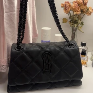 Svart axelväska från Steve Madden - Säljer min snygga svart quiltad axelväska från Steve Madden. Väskan har kedjehandtag och ett rymligt inre med flera fack. Perfekt för både skolan och speciella tillfällen💕köptes för 1200kr från ecoskor som inte säljer väskan längre🥰