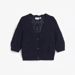 Blå kofta med spetsmönster - Snygg blå kofta med spetsmönster och trekvartsärmar. Perfekt för en stilren och elegant look. Koftan har knappar framtill och en v-ringad design. OBS andra bilden är lånad den jag säljer är blå