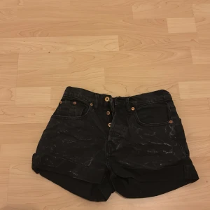 Svarta jeansshorts med knappar - Snygga svarta jeansshorts med knappar framtill och upprullade ben. Perfekta för en avslappnad stil.