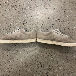 Gråa mocka sneakers - Säljer ett par galet stiliga och sköna gråa mocka sneakers. Skorna har klassisk snörning och en vit sula. Perfekta för en avslappnad stil.