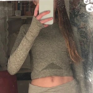 Grå croppad tröja från Relode - Säljer en grå croppad tröja från Relode. Tröjan har långa ärmar med hål för tummarna och ett diskret mönster. Perfekt för en sportig look eller avslappnad stil.