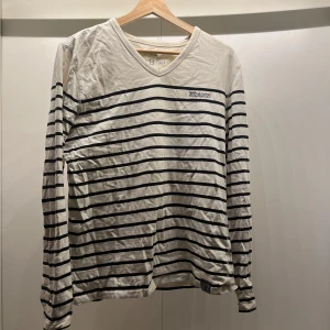 Randig långärmad tröja  - Säljer en klassisk vit och svart randig tröja. Tröjan har en v-ringad hals och långa ärmar, perfekt för en avslappnad stil. Passar bra till både jeans och chinos. Står XL men passar allt från M-XL😇