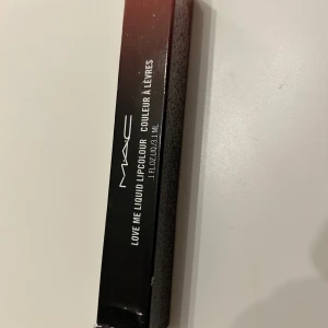 MAC Love Me Liquid Lipcolour 497 Feel Me? - MAC Love Me Liquid Lipcolour i nyansen 497 Feel Me? är en flytande läppfärg med en mjuk applikator. Förpackningen har en elegant design i svart och koppar. Perfekt för att ge läpparna en intensiv och långvarig färg.