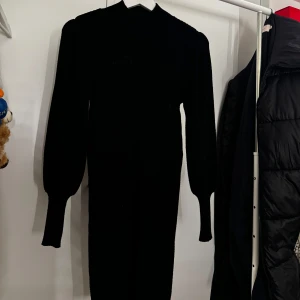 Svart långärmad klänning - (Priset beror på att den är helt ny och aldrig använts!) Elegant svart klänning med långa ärmar och en figurnära passform. Perfekt för en stilren look. 
