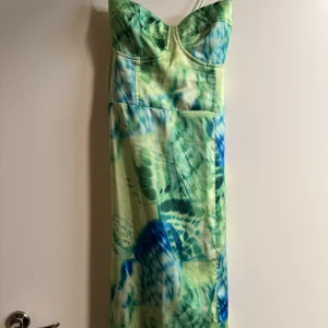 Grön och blå klänning med mönster - Snygg långklänning med grönt och blått mönster. Klänningen har smala axelband och en smickrande passform. Perfekt för somriga dagar! 