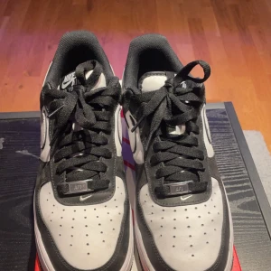 Nike Air Force 1 i svart och vitt - Snygga Nike Air Force 1 sneakers i klassisk svart och vit färgkombination. Skorna har en stilren design med svart snörning och den ikoniska Nike-loggan på sidan. Perfekta för en casual look. Kommer även med crease skydd!