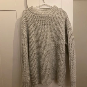 Grå stickad tröja från 157 - Mysig grå stickad tröja från 157 i storlek S. Perfekt för kyliga dagar med sin ribbade design och långa ärmar. Enkel och stilren, passar till det mesta i garderoben.