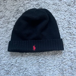 Mössa från Polo Ralph Lauren - ❗️VILL HA SÅLD SNABBT❗️   Snygg svart mössa från Polo Ralph Lauren med röd logga. Skön och snygg mössa i bra skick! ❗️Pris kan diskuteras❗️
