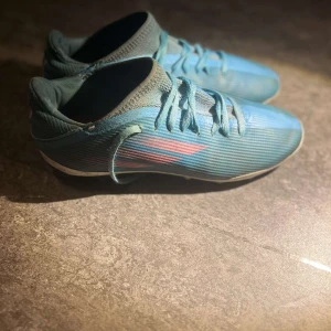 Blå fotbollsskor med snörning - Snygga blå fotbollsskor med snörning och en stilren design. Skorna har en ljusblå ovandel med mörkare detaljer och en slitstark sula med dobbar för bra grepp på planen.