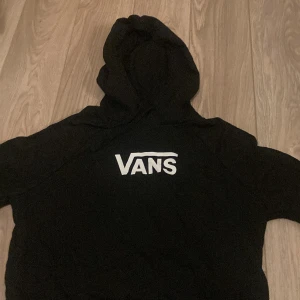 Svart hoodie från Vans - Säljer en klassisk svart hoodie från Vans med deras ikoniska logga i vitt på bröstet. Perfekt för en avslappnad stil.