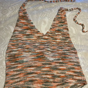 Somrig stickad topp från Shein - Säljer en flerfärgad stickad topp från Shein med ett randigt mönster i orange, grön och beige. Toppen har  knytband i ryggen och är sparsamt använd! 
