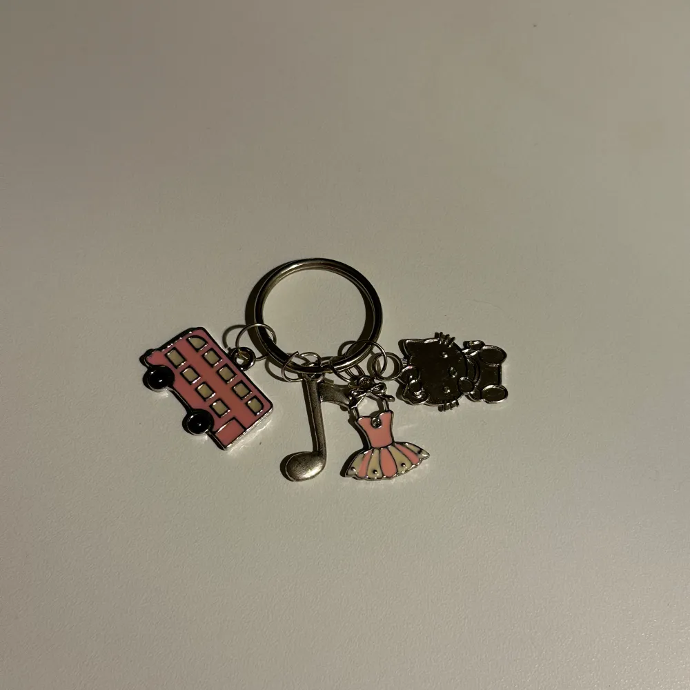 Charmig nyckelring med flera berlocker: en rosa buss, en klĂ€nning, en musiknot och en svart hello kitty.đ±đœAnvĂ€nd gĂ€rna âköp nuâ!đđ. Asusteet.