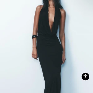 Svart långklänning med djup urringning från Zara - Elegant svart långklänning med djup v-ringad urringning och öppen rygg. Klänningen har en figurnära passform som framhäver silhuetten. Oanvänd med lappar kvar💗