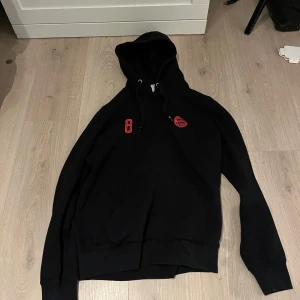 Svart hoodie med Goretzka-tryck - Snygg svart hoodie med rött tryck av siffran 8 och namnet Goretzka på ryggen. Perfekt för fotbollsfans! Den har en justerbar huva med snören! 