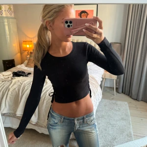 Svart croppad topp med snörning - Snygg svart croppad topp med långa ärmar och snörning i midjan.