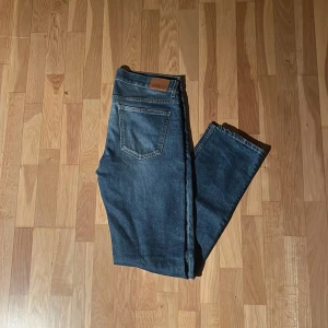 Blå jeans från Oscar Jacobson - Snygga blå jeans från Oscar Jacobson med klassisk femficksdesign och diskret logga på bakfickan. Jeansen har en slimmad passform. Modellen heter Albert 