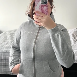 Grå hoodie från Champion - Säljer en grå hoodie från Champion med dragkedja och fickor framtill. Den har långa ärmar och en bekväm huva.