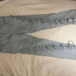 Jeans med snörning - Jeans med snörning från HM studio Collection. (Aldrig använt) Byxorna är enligt storlek S men ganska små i storleken vilket gör att XS (32-34) förmodligen har bäst matchande passform till dessa. Däremot gör snörningen att man kan anpassa storleken lite till vad man känner för, både tightare eller lösare. På samma sätt går det att välja mellan att bära de som raka eller bootcut/flare (om man gör bredare snörning längre ner). Tveka inte att kontakta mig om du vill se fler bilder på de! 💙🩵💙