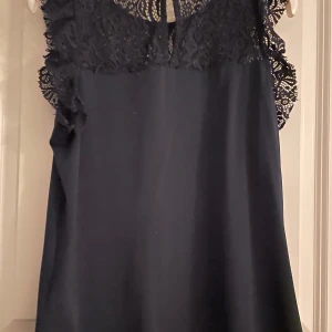 Marinblå blus  - Marinblå blus från Vero Moda, sparsamt använd och i bra skick. Kort spets på ärmen, så blusen blir som ett linne. 