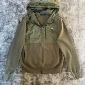 J. Lindberg cardigan - Säljer min snygga j.Lindeberg cardigan eller hybrid tröja i storlek M. Skick enligt bilder inga hål såklart. Den e ovanlig eftersom den tillverkas inte längre 