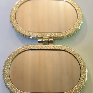 Söt fickspegel - Söt fickspegel med 2 spegelglas. Utsidan har ett mjukt blommigt tyg, knäppet är en liten fjäril och vackra mönster runt spegelglasen. Mått är ca: 7.5 × 6 cm. Denna finns i annan form/färg, se mina andra annonser. Perfekt att ha med sej i väskan.