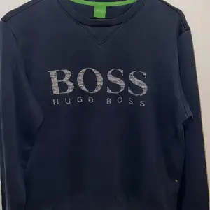 En sweatshirt från Hugo Boss. Den har ett stort BOSS-tryck på framsidan och mellan stora där de står Hugo boss och är i storlek M, men passar S. Tröjan är i bra skick. För att va en gammal modell 