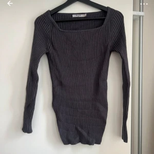 Grå ribbad tröja - Säljer en snygg grå ribbad tröja från NAKD. Den är långärmad och har en fyrkantig halsringning som ger en stilren look. Perfekt för höst och vinter, och passar både till vardags och fest. Tröjan är i bra skick och superbekväm!