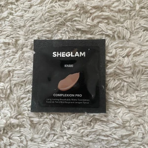 Sheglam Complexion Pro Foundation i nyansen Khaki - Säljer en Sheglam Complexion Pro Foundation i nyansen Khaki. Denna foundation är långvarig och andas, med en matt finish som ger en jämn och fin hudton. Perfekt för en naturlig look som håller hela dagen!