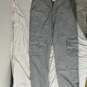 Grå bxor - Snygga gråa byxor med flera fickor. Byxorna är i gott skick och har aldrig använts. Säljs för 100 kr