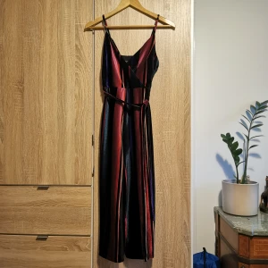 (32/34) Randig byxdress / jumpsuit från Primark - Snygg glansig byxdress från Primark med färgglada ränder i svart, rött, blått och lila. Märkt 34, men liten i storlek. Trekvartsbyxor. 💜